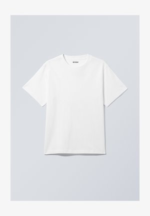 Valkoinen puuvillapaita, jossa on pyöreä kaula-aukko, lyhyet hihat ja rento leikkaus. Kauluksessa on merkkilapuke, jossa lukee "WEEKDAY".