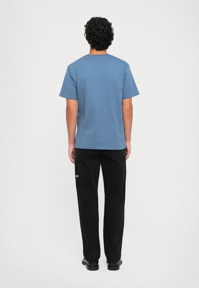 Blaue kurzärmelige T-Shirt mit Rundhalsausschnitt, kombiniert mit lockeren schwarzen Hosen. Schlichtes Design, weicher Stoff und minimalistische Akzentdetails.