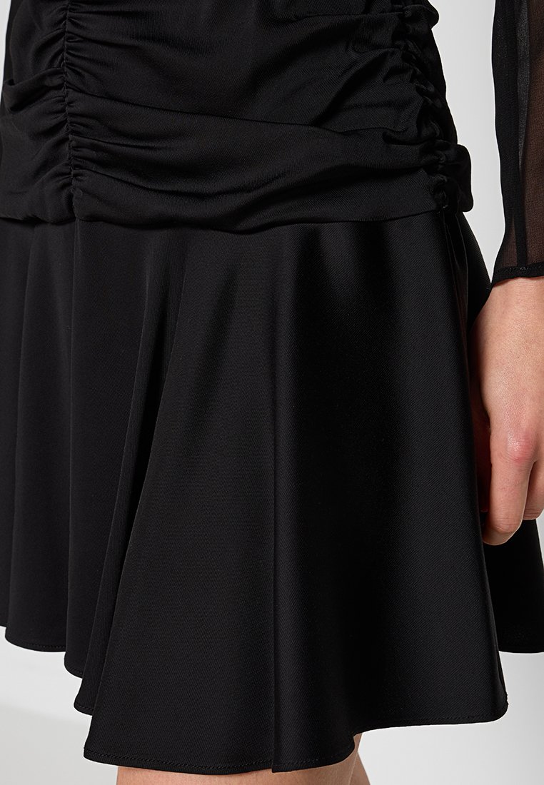 Vestido negro con corsé fruncido y falda acampanada. Hecho de tela suave con una textura fluida y un brillo sutil.