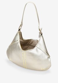 Bolso de mano de cuero plateado metálico con forma curva, acentos de tachuelas doradas en las costuras y parte superior con cremallera. Cuenta con una sola correa para el hombro.