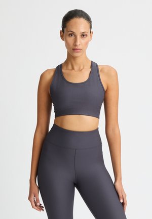 Grijze geribde sportbeha met een scoop halslijn, gecombineerd met bijpassende hoge geribde leggings. Gladde textuur, nauwsluitend ontwerp.