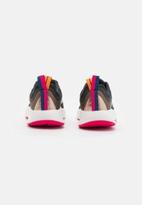 Sportovní boty s tmavým svrškem, béžovými akcenty a silnou bílou podrážkou. Mají barevné poutka na patě v oranžové, růžové a modré barvě.