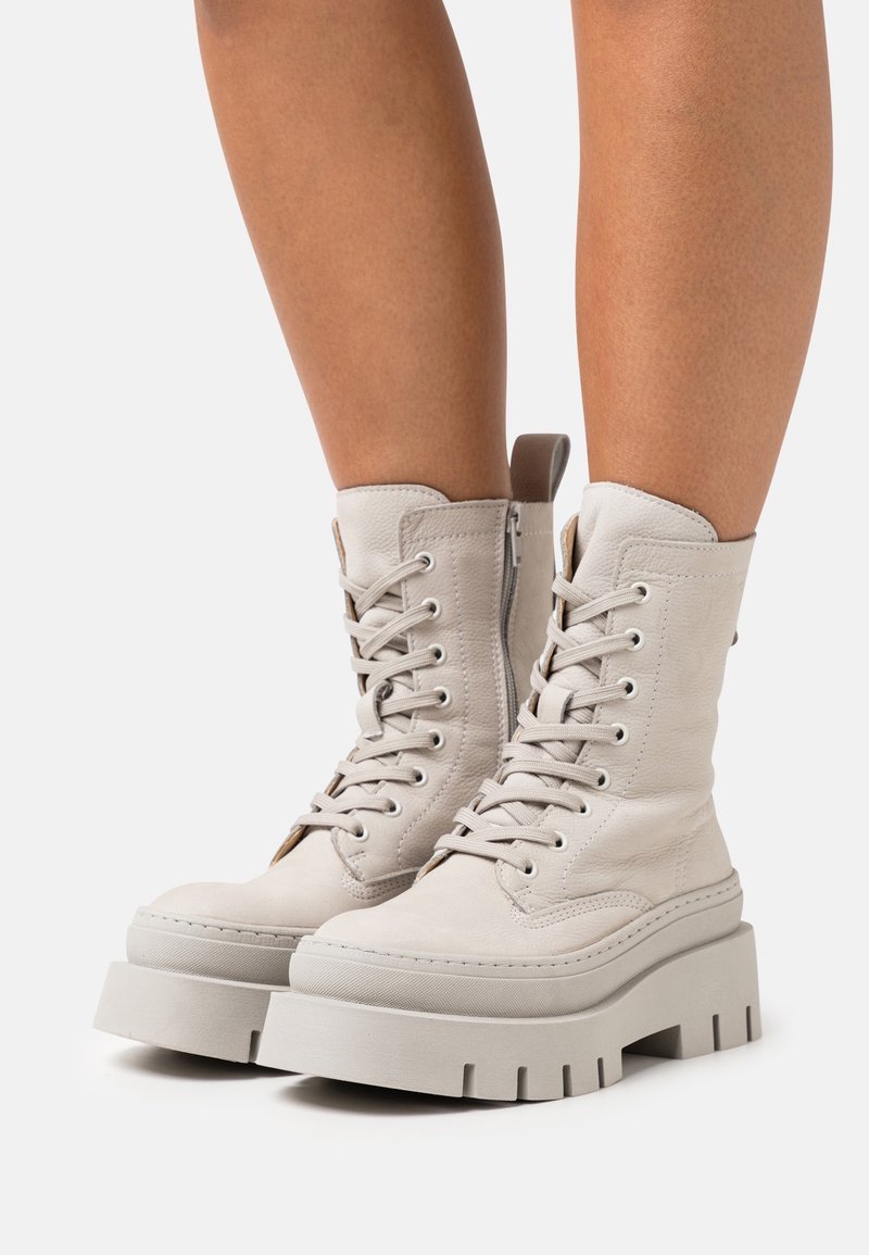 Bottes chevilles en cuir gris à lacets avec une semelle plateforme épaisse, dotées d'une fermeture éclair latérale et d'un motif texturé, conçues pour un maintien sûr.