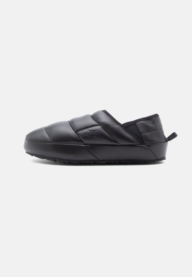 Fekete slip-on cipők steppelt szintetikus anyagból, texturált felülettel és gumitalppal, oldalán logó részlettel.