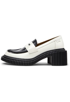 Zwart-witte leren loafer met tweekleurig design, voorzien van een grove geribbelde platformzool en blokhak, met een riemdetail over de bovenkant.