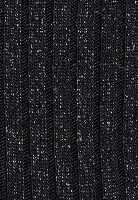 Schwarzer gerippter Strickstoff mit feinen silbernen metallischen Fäden, der vertikale Streifen und eine weiche Textur aufweist.