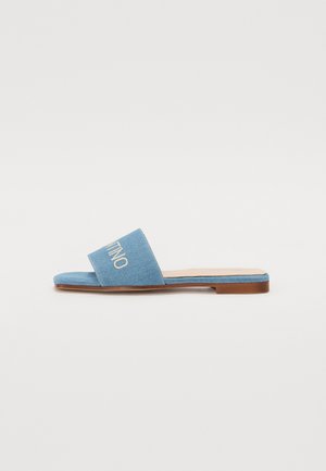 Sandálias deslizantes em denim com sola plana, de cor azul clara, tira larga e detalhe em logo bordado. Apresentam uma textura suave e um design minimalista.