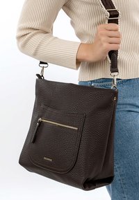 Braune Schultertasche aus Leder mit genarbter Textur, ausgestattet mit einer vorderen Reißverschlusstasche und einem verstellbaren Riemen. Einfaches, rechteckiges Design.