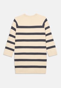 Beige strikkegenser med mørk marine horisontale striper. Har ribbet mannsomme og trekvart lange ermer. Glatt tekstur.