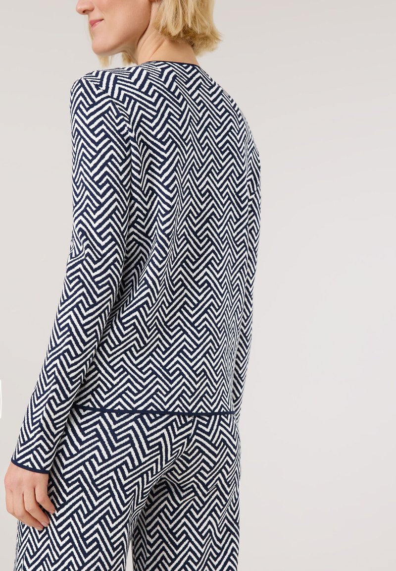 Top de manga larga en azul marino y blanco con un diseño geométrico de zigzag, con un escote redondo y un corte relajado. Tejido de punto texturizado.