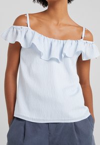 Lichtblauw gestreept off-the-shoulder topje met een gekreukelde halslijn, dunne schouderbandjes en een zachte stofstructuur. Casual en relaxed fit.