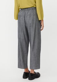 Szare szerokie spodnie w paski z elastycznym pasem, tylnymi kieszeniami naszywanymi i luźnym krojem, zestawione z czarnymi butami.