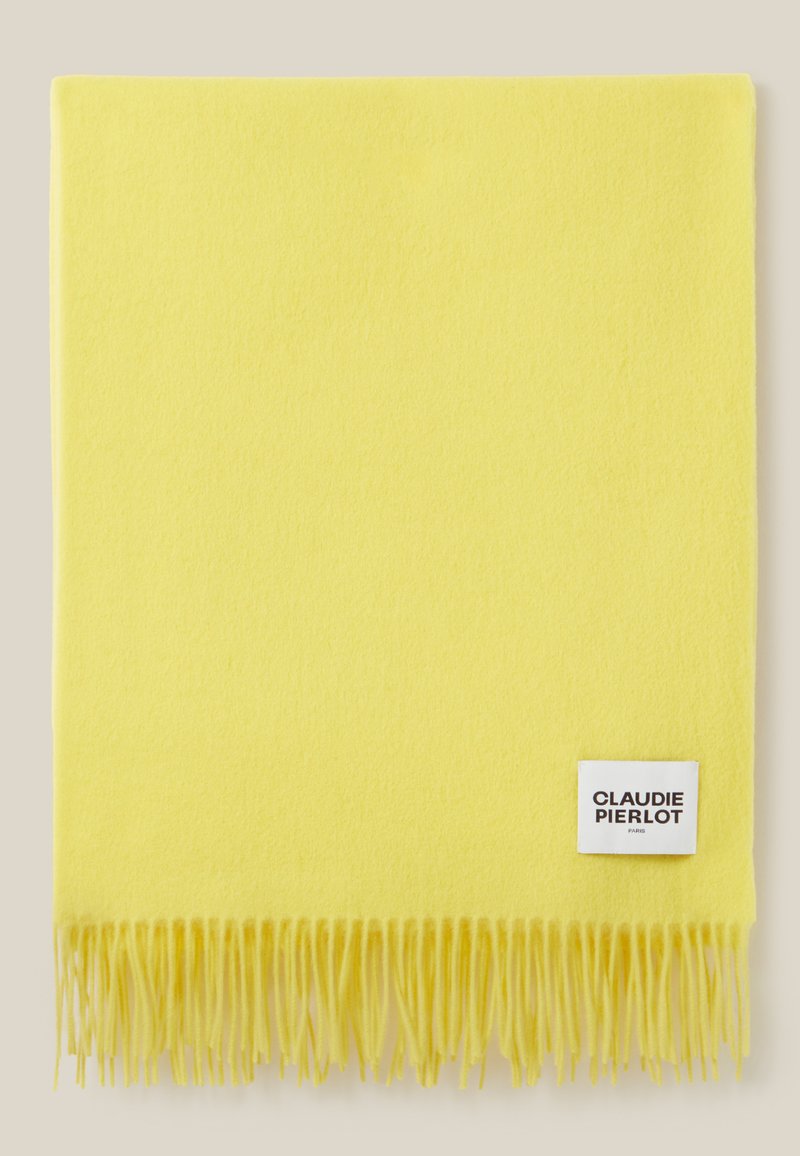 Gelber Schal aus weichem Stoff, mit fransigen Kanten. Ein weißes Etikett mit "CLAUDIE PIERLOT" ist in eine Ecke genäht.