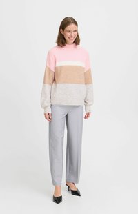 Pull léger en blocs de couleurs rose, beige et gris, avec un col montant et des manches amples, associé à un pantalon gris ajusté.