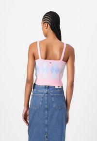 Pink and blue knitted crop top with a diamond pattern, wide straps, and a fitted design, paired with a high-waisted denim skirt.