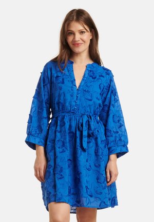 Blauwe geborduurde jurk met een strik taille, voorzien van driekwart mouwen en bloemmotieven door het geheel. Gemaakt van lichtgewicht stof.