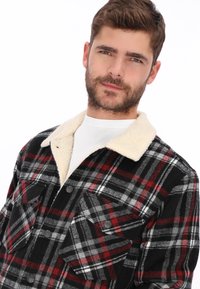 Chaqueta de cuadros para hombre que presenta un patrón en negro, rojo y gris, con un cuello de forro polar color crema, confeccionada con una mezcla de lana.