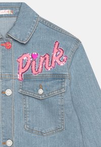Giacca di denim di colore azzurro chiaro con un'applique in paillettes rosa "Pink" sul petto. Presenta bottoni in metallo argentato e due tasche frontali.