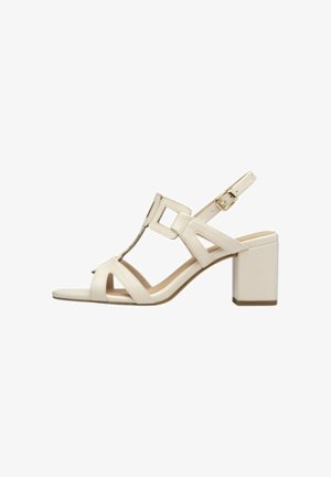 Sandalo beige con punta aperta, tacco a blocco, cinturino regolabile alla caviglia con fibbia dorata e design geometrico traforato sulle fasce laterali.