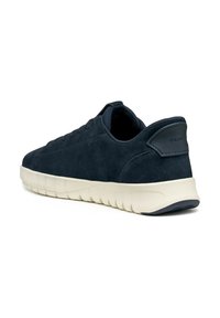 Zapatilla de ante azul marino con una superficie texturizada, suela de goma blanca y diseño minimalista. Presenta un logotipo en el talón y un cordón sutil.