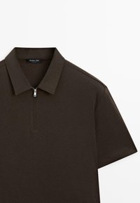 Ciemnobrązowa koszulka polo z krótkim rękawem, kołnierzykiem i krótkim zamkiem z przodu, widok z góry na białym tle.