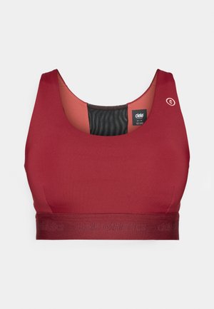 Red sports bra with a scoop neckline, made from smooth fabric. Features a textured black inner lining and a logo on the shoulder.
