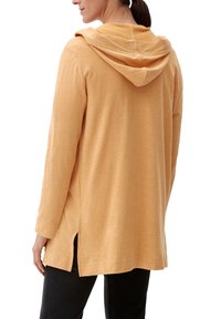 Felpa gialla a maniche lunghe con una vestibilità rilassata, dotata di una texture morbida, fessure laterali e cappuccio. I polsini elasticizzati completano il design.