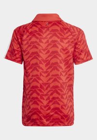 Röd kortärmad pikétröja med ett strukturerat mönster av överlappande trianglar, en krage och vita detaljer på ärmarna.