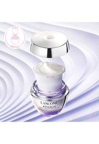 Przezroczysty szklany słoik z fioletową podstawą, srebrną pokrywką i białym kremem w środku. Różowy symbol wskaźnika uzupełniania. Gładka, błyszcząca powierzchnia.