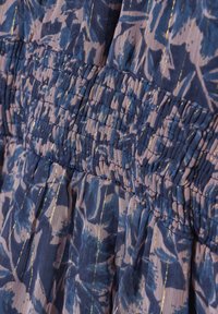 Kukallinen mekko, jossa on kiristettävä vyötärö sinipunaisina sävyinä, kultaisilla korostusraidoilla ja pehmeällä, tekstuurilla varustetulla kankaalla.