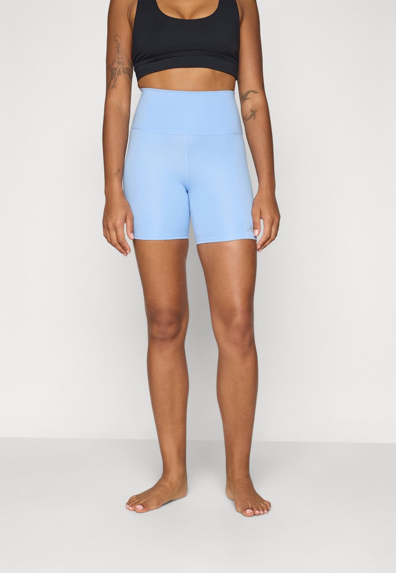 Light blue high-waisted shorts with a smooth texture. Paired with a black crop top, showcasing a fitted design and athletic style.