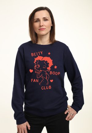 Marineblå sweatshirt med et rødt grafisk motiv af en tegnefilmsfigur, tekst "BETTY BOOP FAN CLUB" samt stjerne- og hjerte-accenter. Lange ærmer, afslappet pasform.