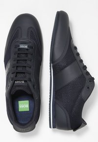 Marinblå sneakers med en slät läder- och mesh-övre, rund tå, snörning framtill och kontrasterande vit sula. Har märkesaccenter.