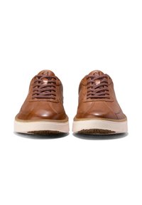 Hnědé kožené tenisky s kulatou špičkou, koženými tkaničkami a kontrastní krémovou gumovou podrážkou. Obsahují embossované logo na jazyku.