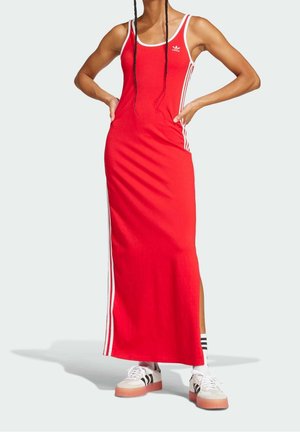 Rød maxikjole med tynde stropper, hvide sidelommer og en sideslids. Bæres med hvide sneakers med sorte striber og pink såler.