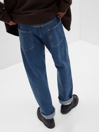 Denimjeans i en mellomblå vask, med en avslappet passform, oppbrettede hemmer og to baklommer. Brukt med en mørk, strukturert genser.