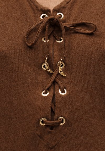 Καφέ ύφασμα με διασταυρούμενο κορδόνι μέσα από μεταλλικά οφθαλμούς, δεμένο στην κορυφή με δύο μικρά διακοσμητικά χρυσά φτερά στα κορδόνια.