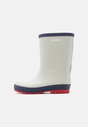 Botte de pluie en caoutchouc couleur crème clair avec une bande supérieure bleu marine et une semelle rouge. Présente une surface texturée et un logo sur le côté.