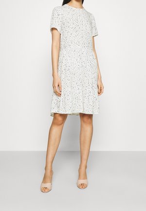Robe à motif floral en tissu léger, longueur genou avec manches courtes, encolure ronde, taille légèrement froncée, associée à des talons ouverts nude.