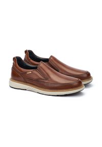 Zapatos marrones de piel slip-on con un acabado suave, suela en contraste color beige, paneles laterales elásticos y un detalle de costura sutil.