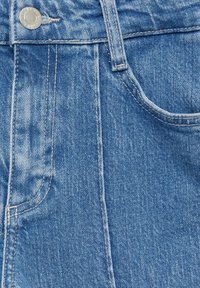 Gros plan sur un jean en denim bleu montrant la poche avant, la boucle de ceinture, les détails de couture et le bouton en métal argenté à la taille.
