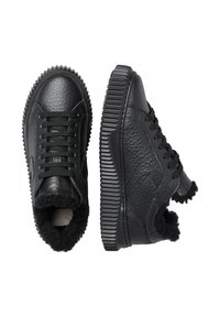 Sneakers neri con una parte superiore in pelle texture, punta rotonda e una robusta suola in gomma seghettata. Foderati in pelliccia nera attorno alla caviglia.