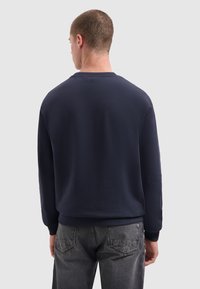 Marineblauwe sweatshirt met lange mouwen, ronde hals en geribde manchetten. Gladde textuur, minimalistisch ontwerp en subtiele logodetail op de achterkant.