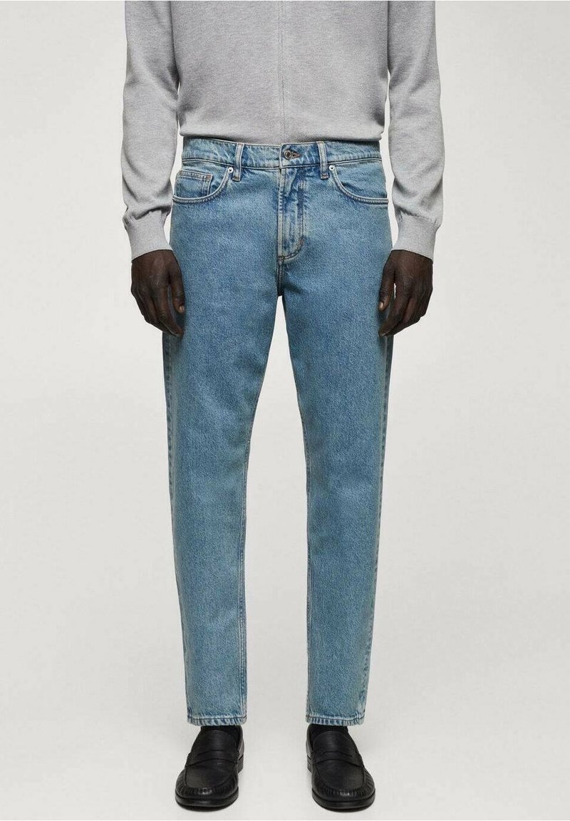 Jeans in denim azzurro chiaro con una vestibilità dritta, design a cinque tasche e leggere sfumature, abbinati a scarpe nere e a un top grigio.