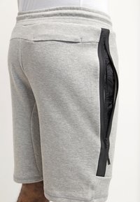 Gray cotton sweat shorts with a black side zipper, ribbed waistband, and a smooth texture. Features a side pocket for storage.