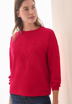 Red sweatshirt with a round neck and long sleeves. Features embossed graphic design on the front. Soft fabric, relaxed fit.