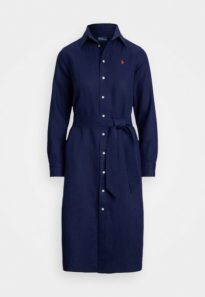 Navy linen shirt dress with long sleeves, collar, button front, and a waist tie. Features a small red logo on the chest.