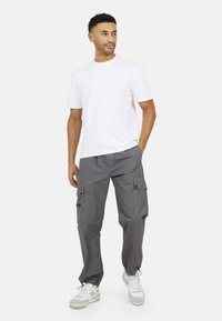 Biała bawełniana koszulka, szare bojówki z kieszeniami bocznymi, luźny krój, lekki materiał, zestawione z białymi trampkami na codzienny wygląd.