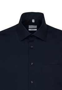 Camicia da uomo blu navy con colletto botton-down, un piccolo motivo a pois all'interno del colletto e taschino sul petto. Realizzata in tessuto morbido.