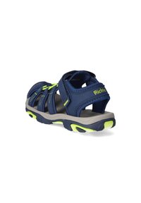 Dunkelblaue und neongrüne Kindersandale für den Außenbereich mit verstellbaren Riemen und dicker Sohle, von der Ferse aus auf einem weißen Hintergrund betrachtet.